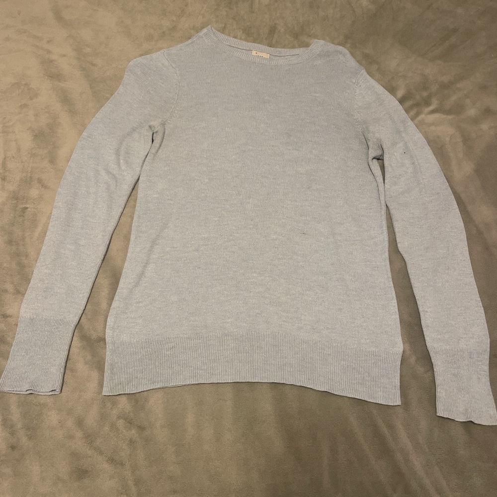 Light grey sweater with a small logo tag, perfect for a casual and cozy look.